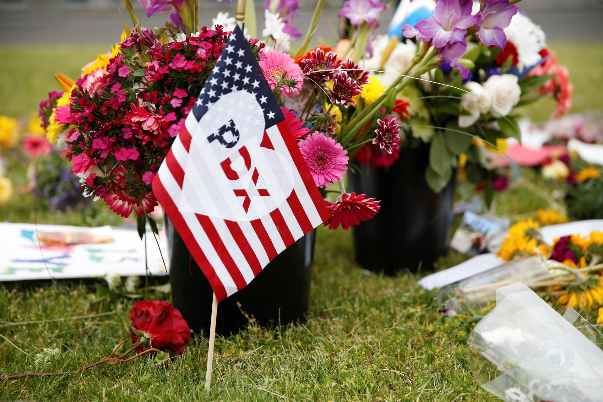 A flag bearing an abbreviation for "Portland" stands at a makeshift memorial.