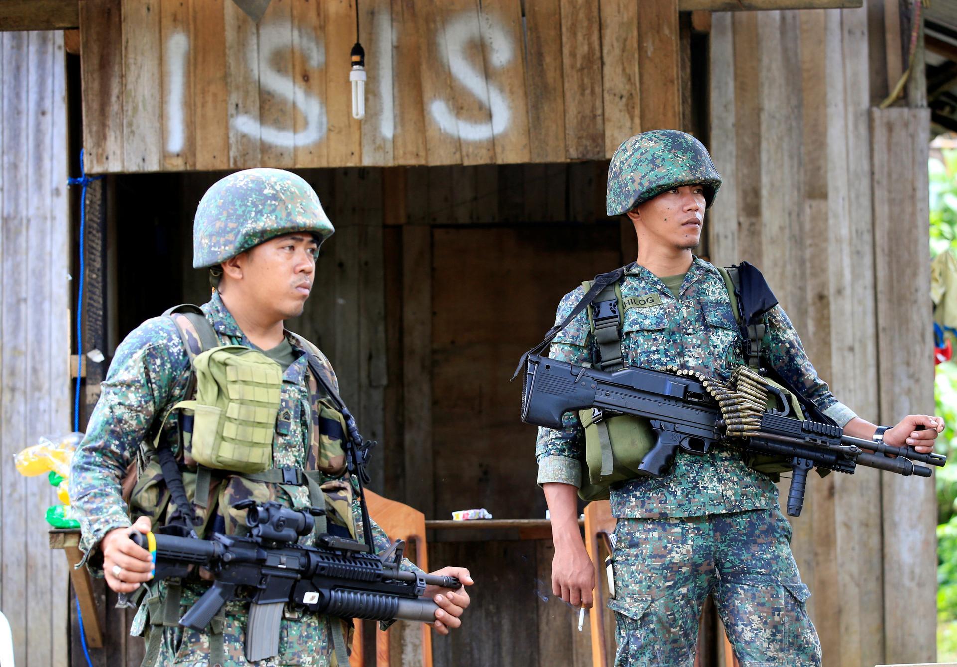 Soldiers stand guard along the main street of Mapandi village as government troops continue their assault on insurgents from the Maute group, who have taken over large parts of Marawi City.