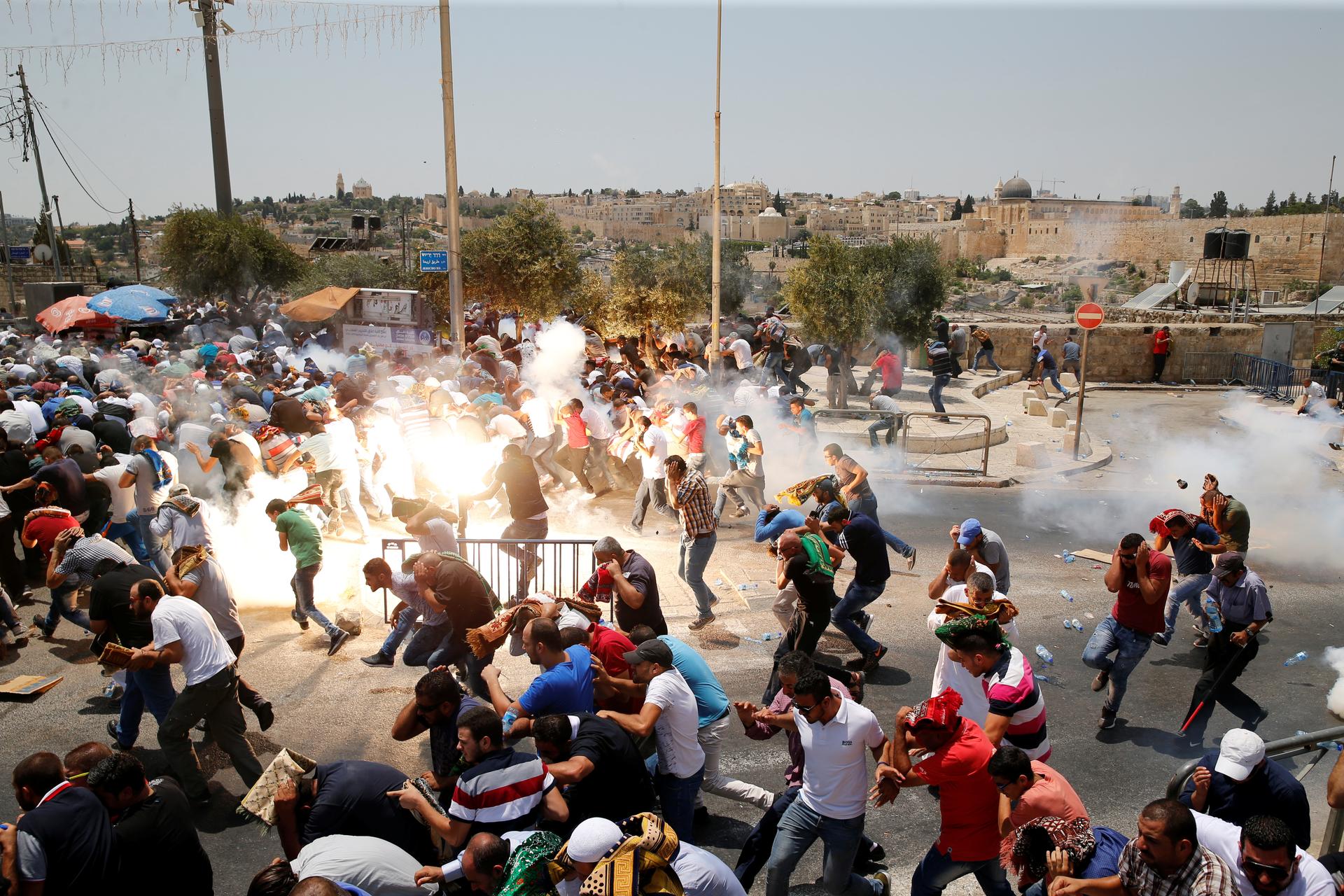Palestinians react following tear gas that was shot by Israeli forces after Friday prayer on a street outside Jerusalem's Old city
