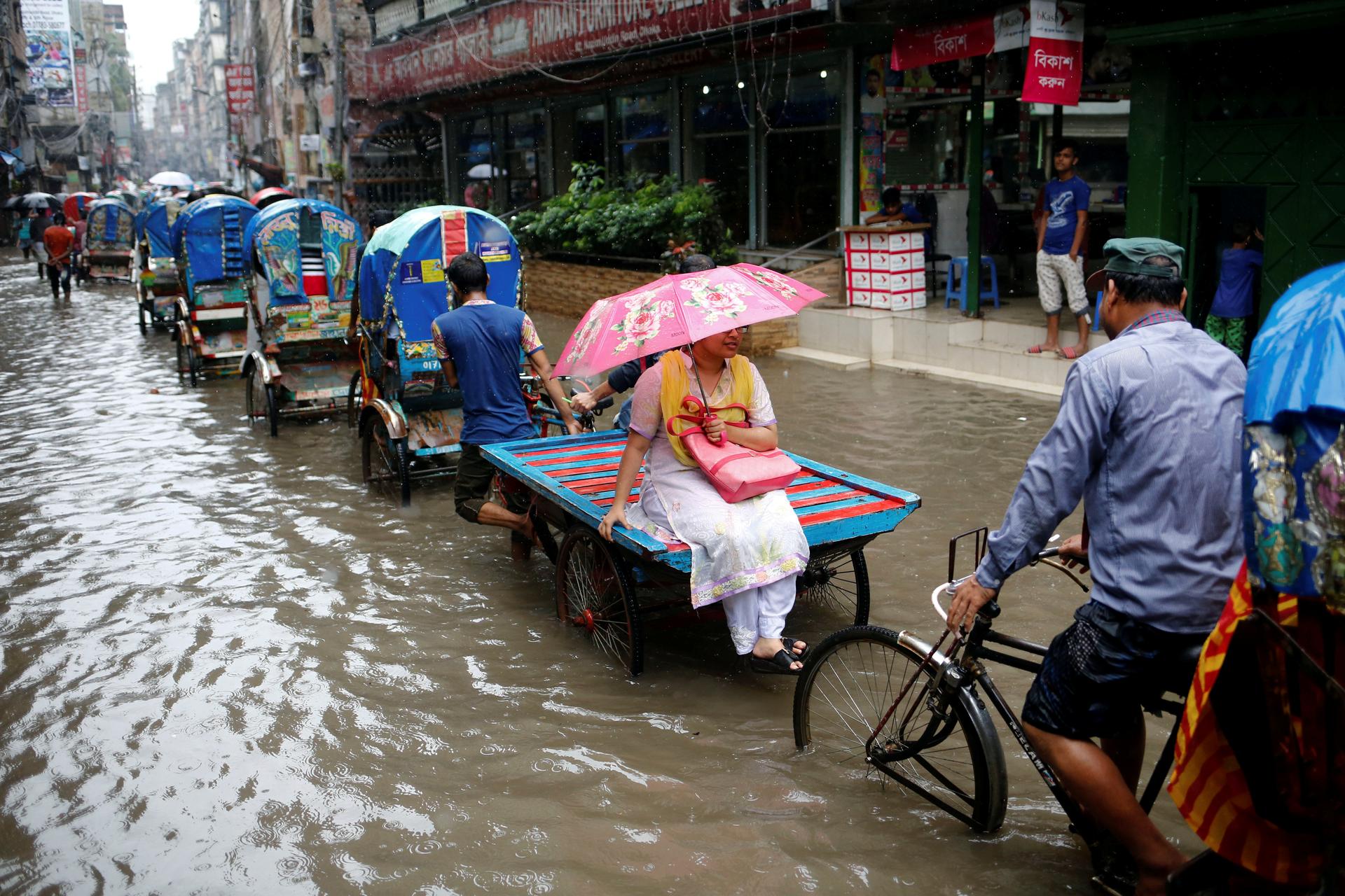 Commuters ride on rickshaws as streets are flooded due to heavy monsoon rains in Dhaka.