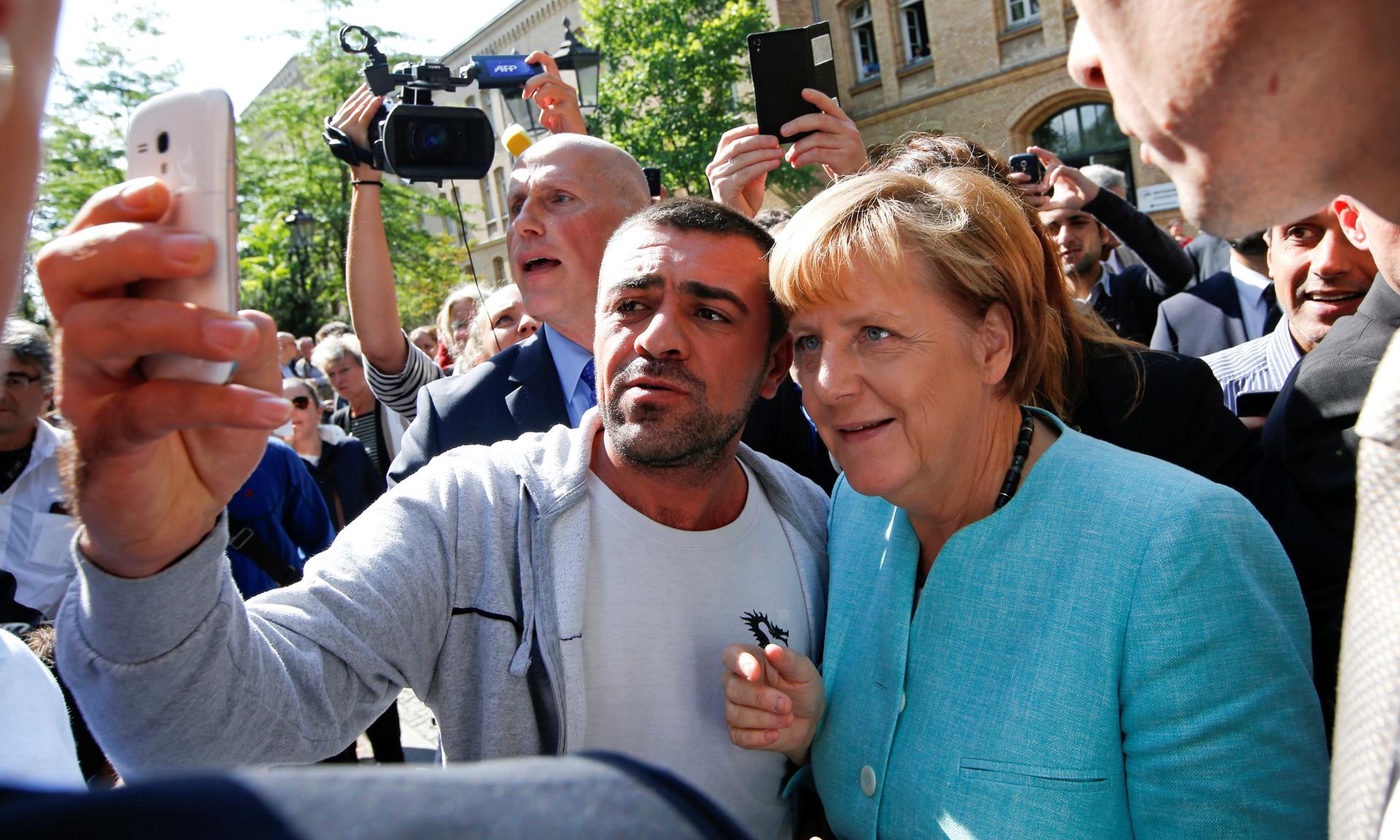 A man who identifies himself as a migrant takes a selfie with German Chancellor Angela Merkel outside a refugee camp near the Federal Office for Migration and Refugees in Berlin, Germany, Sept. 10, 2015.