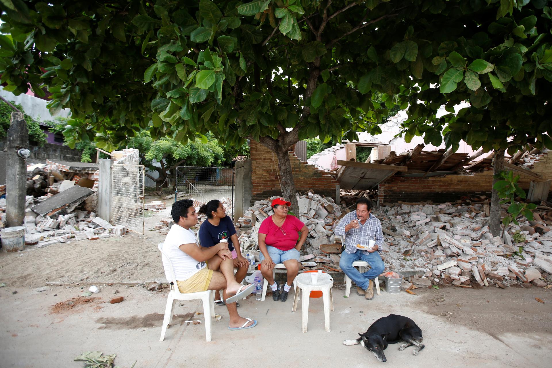 A family sits outside their house destroyed by the earthquake that struck the southern coast of Mexico late on Thursday, in Ixtaltepec, Mexico.