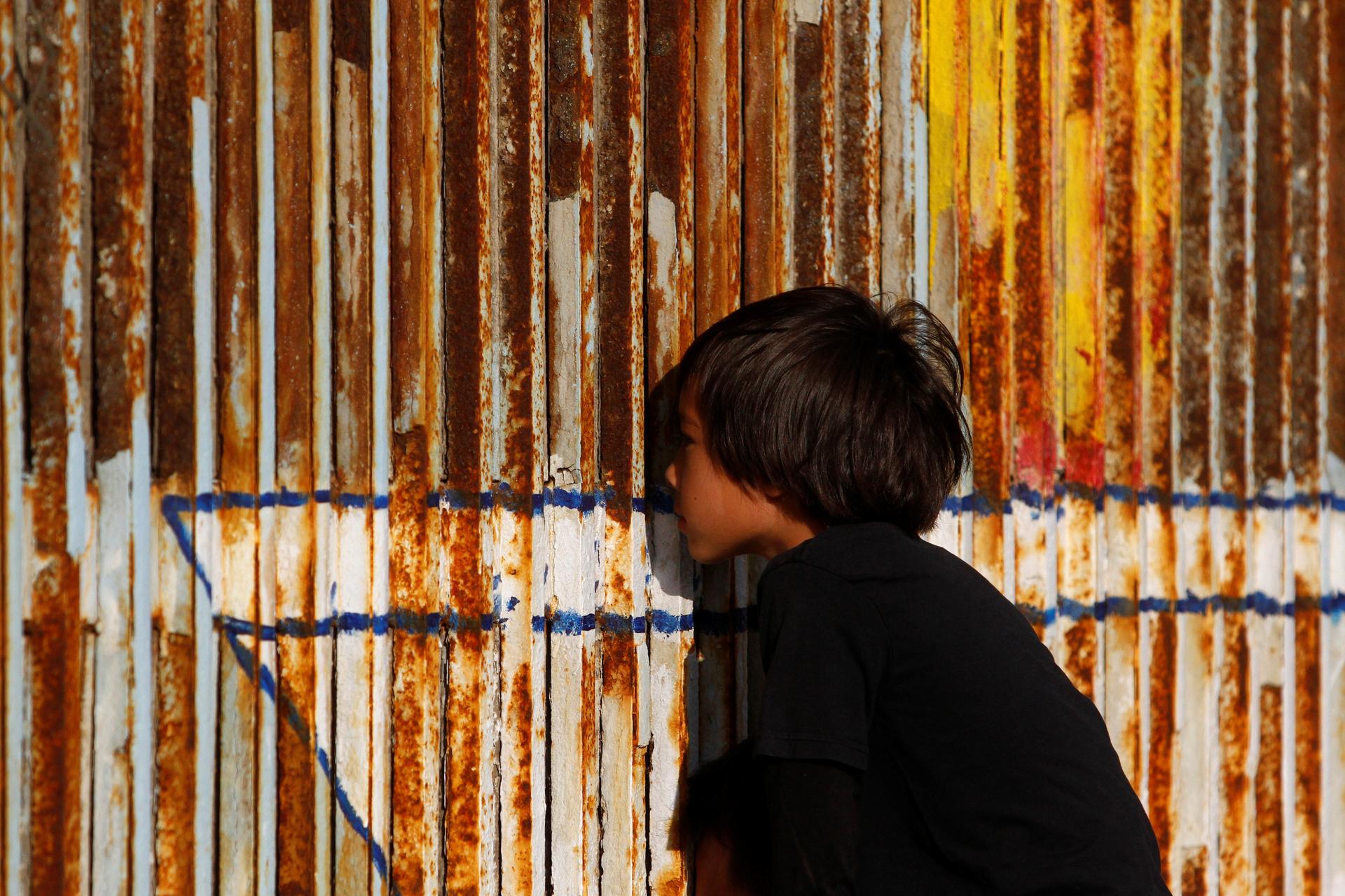 A child peers through the double steel fence that separates the US and Mexico, in Tijuana, last month