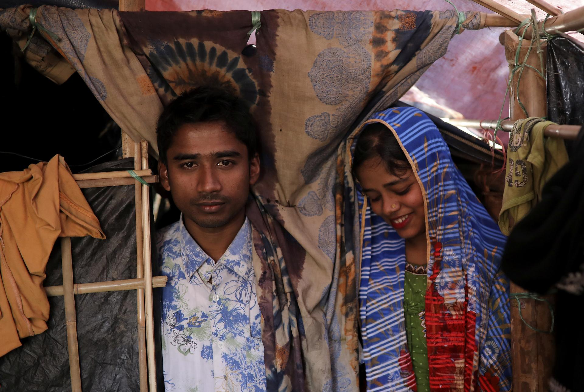 Rohingya refugees Saddam Hussein, 23, and his wife Shofika Begum, 18, pose in their temporary shelter at the Kutupalong refugee camp near Cox's Bazar, Bangladesh