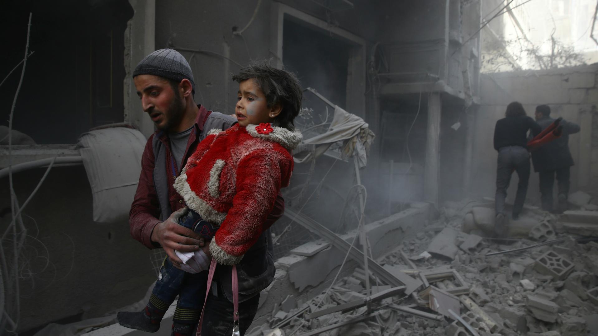 A man holds a child after an airstrike in eastern Ghouta, Syria, Feb. 7, 2018. In the Damascus suburb, besieged by government forces since 2013, about 78 civilians were killed by airstrikes and artillery fire on Tuesday, according to monitors. A further 2