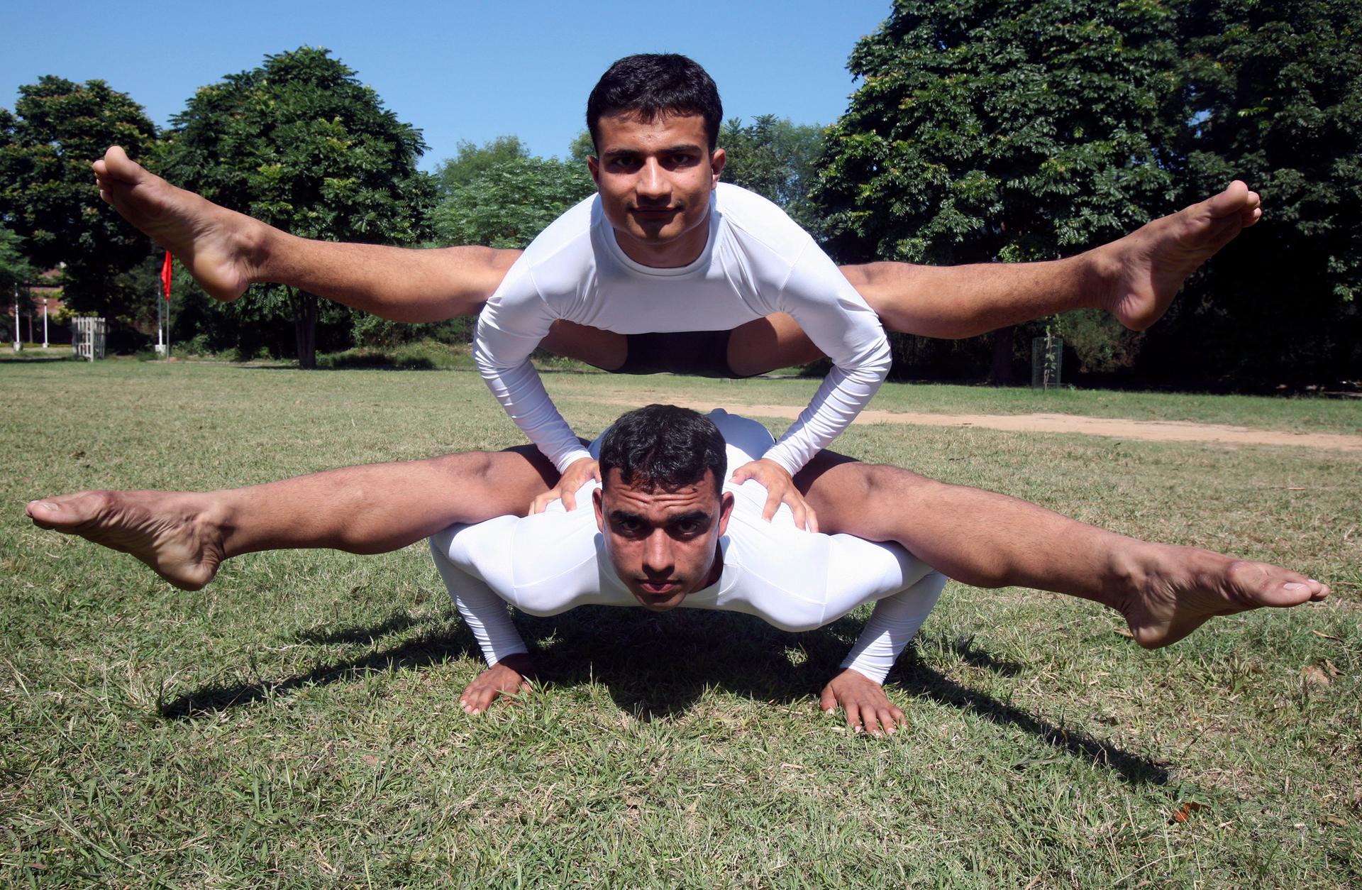 Two men perform difficult pose on grass lawn