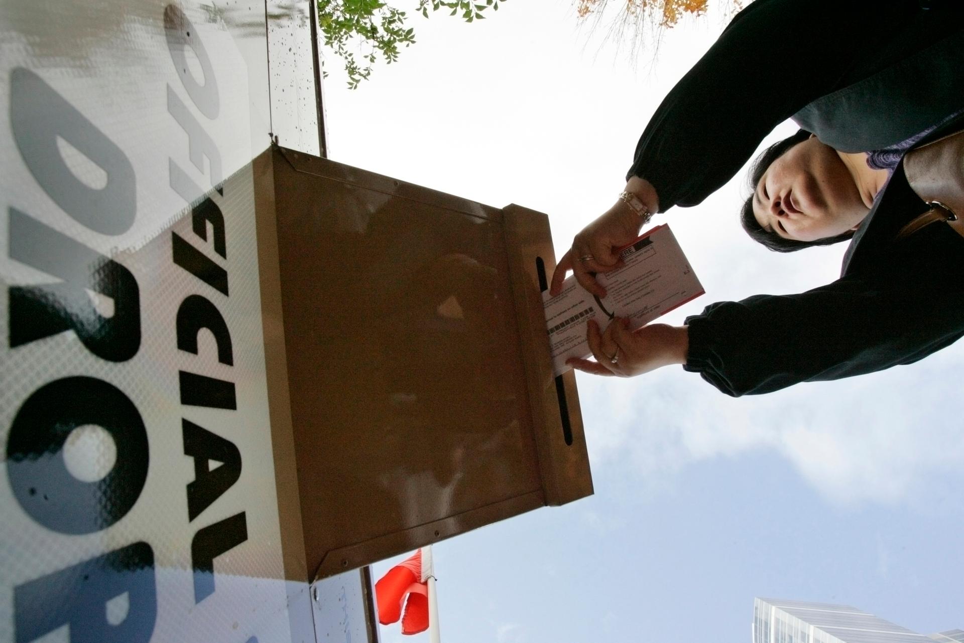 A woman drops her ballot off at a drop-off site