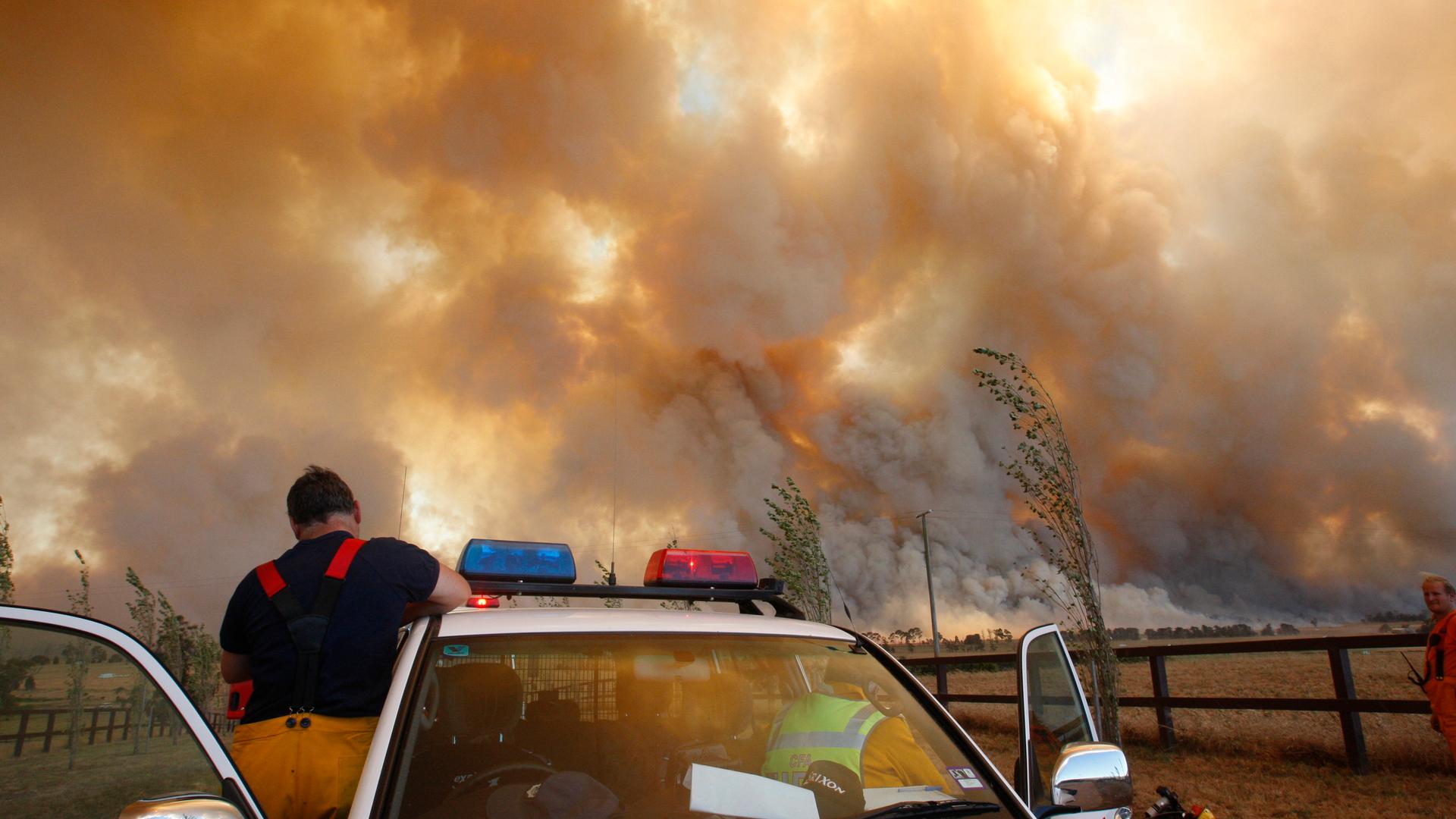 A fireman climbs down from his truck as a bushfire approaches a town outside of of Melbourne, Australia in February, 2009. Officials blamed the dozens of blazes across the country five years ago on a "once in a century" heatwave. With climate change incre