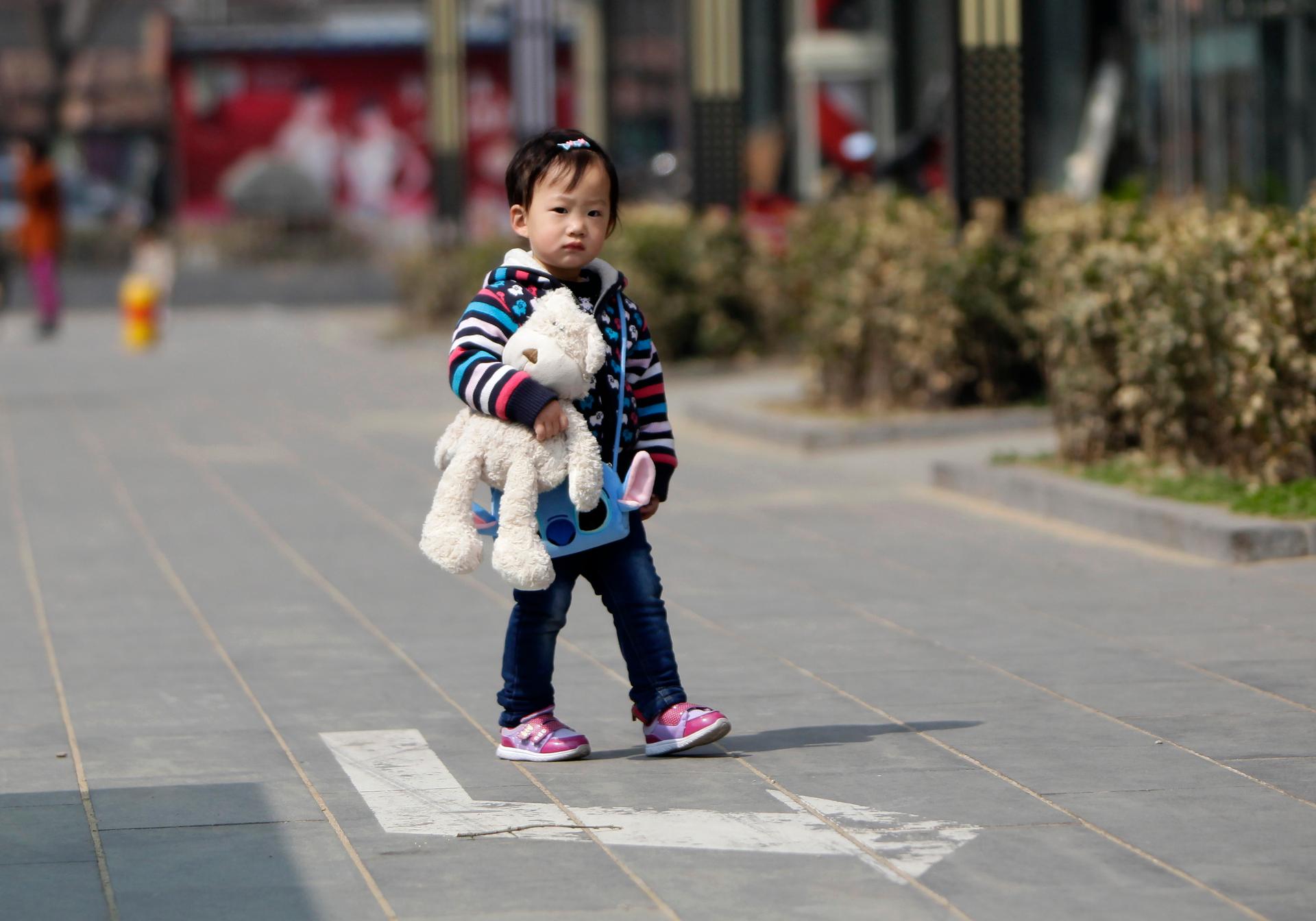 A girl walks along a street in Beijing. China has announced reforms to the policy of allowing most families to have only one child. 