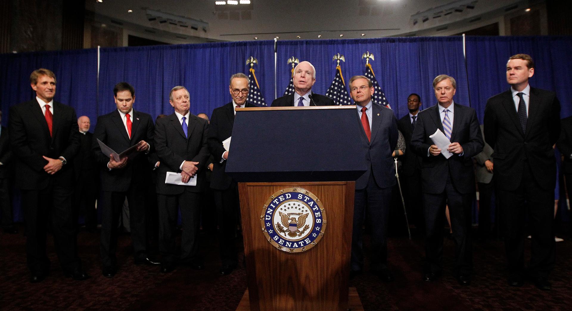 Eight men behind podium with microphones
