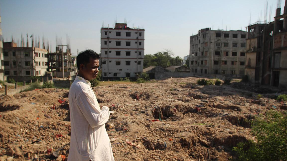 Rafiqul Islam is president of a labor federation based next to the site of the Rana Plaza collapse. In the foreground is a field filled with rubble from the building, and beyond that is the site of the collapse.