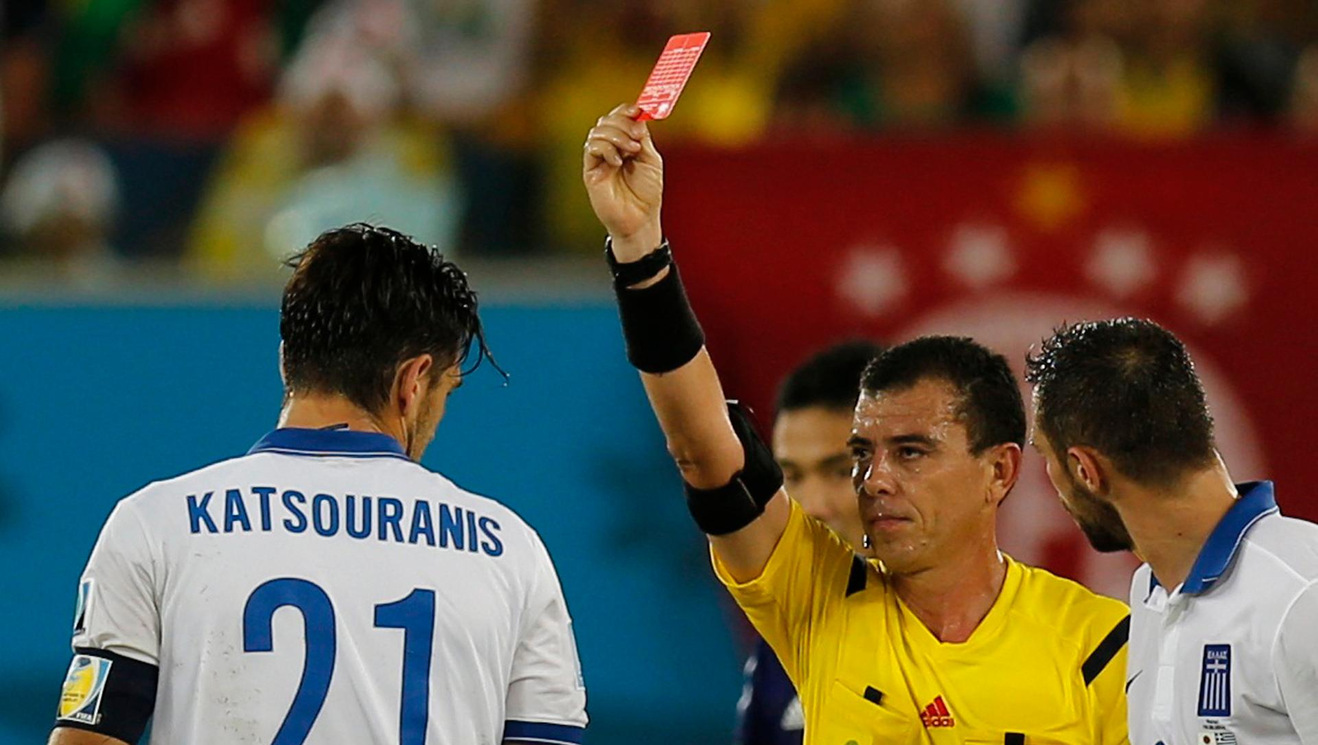 Greece's Kostas Katsouranis (L) receives a red card from referee Joel Aguilar of El Salvador during their 2014 World Cup soccer match against Japan, June 19, 2014.