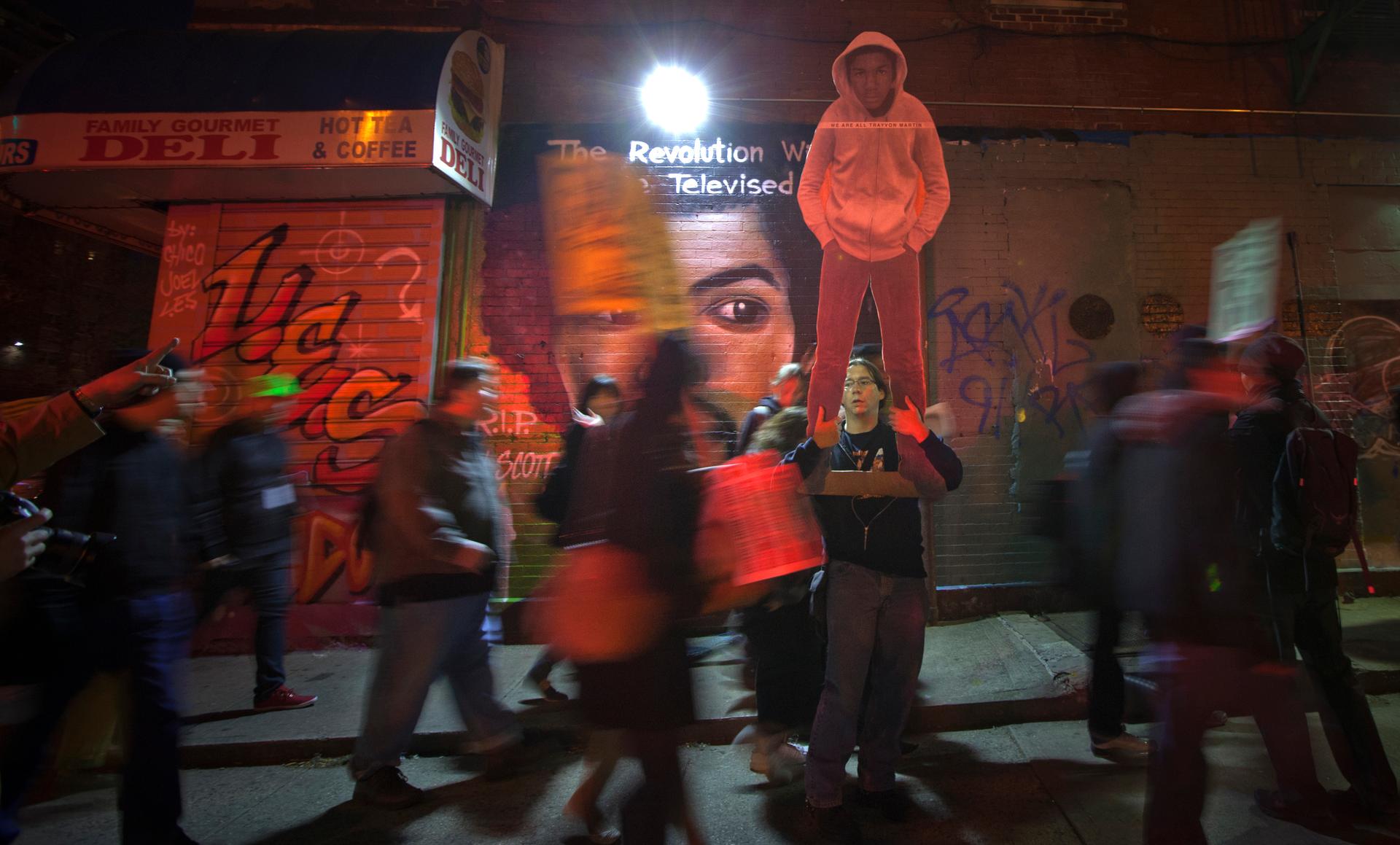 A mural showing Gil Scott-Heron and his trademark phrase, "The Revolution Will Not Be Televised," is the backdrop for protesters marching through the streets of New York in 2012, demanding justice for slain Florida teenager Trayvon Martin.
