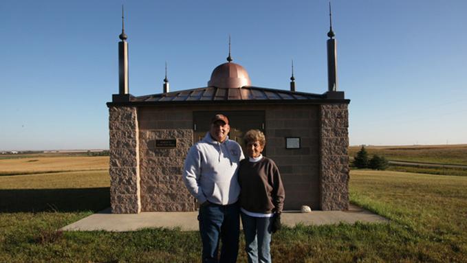 A couple stands in front of a replica of a small mosque