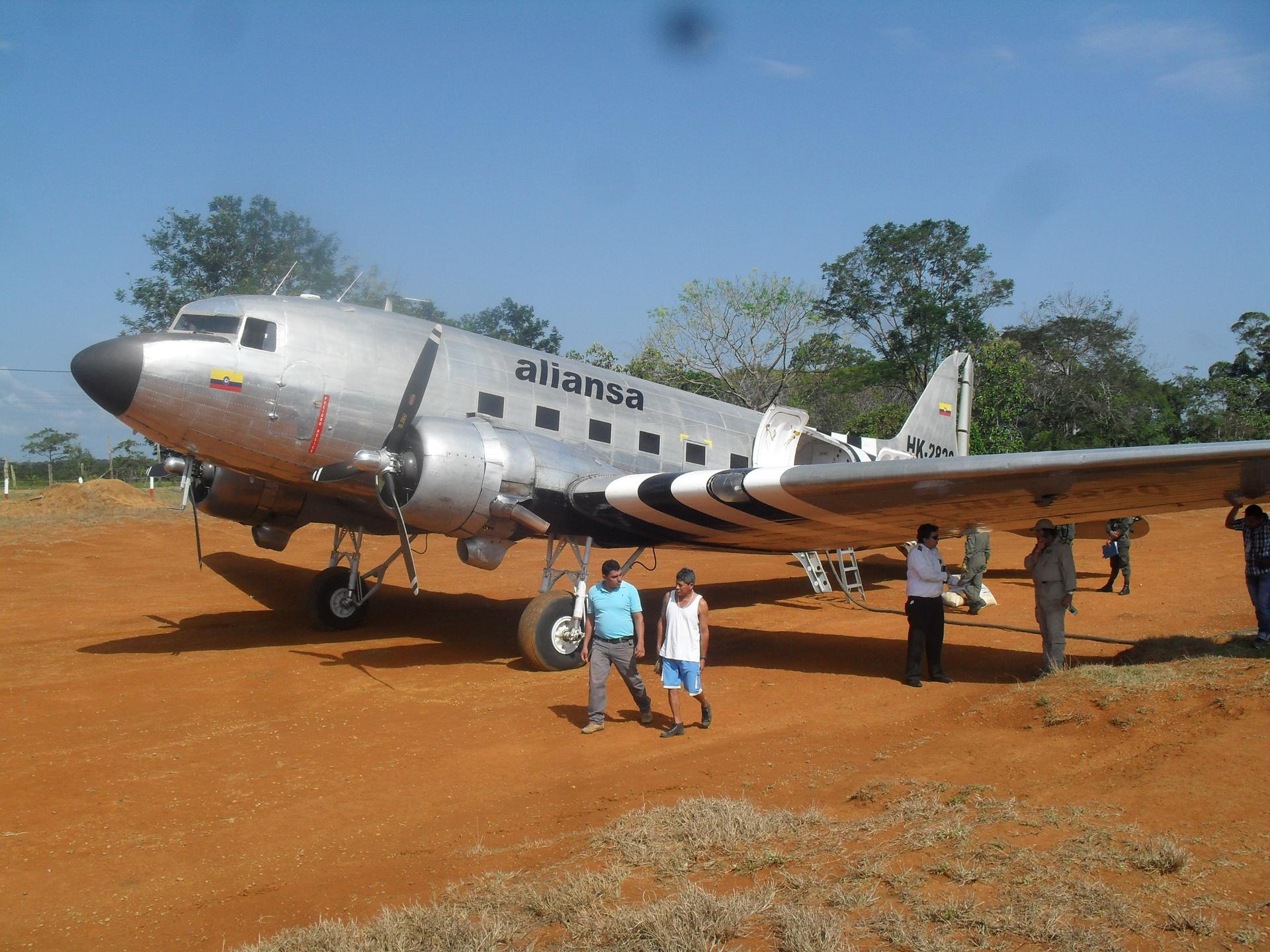 Pilots stand in the shade of the wing of a DC-3 in the hamlet of Miraflores in the Colombian jungle.