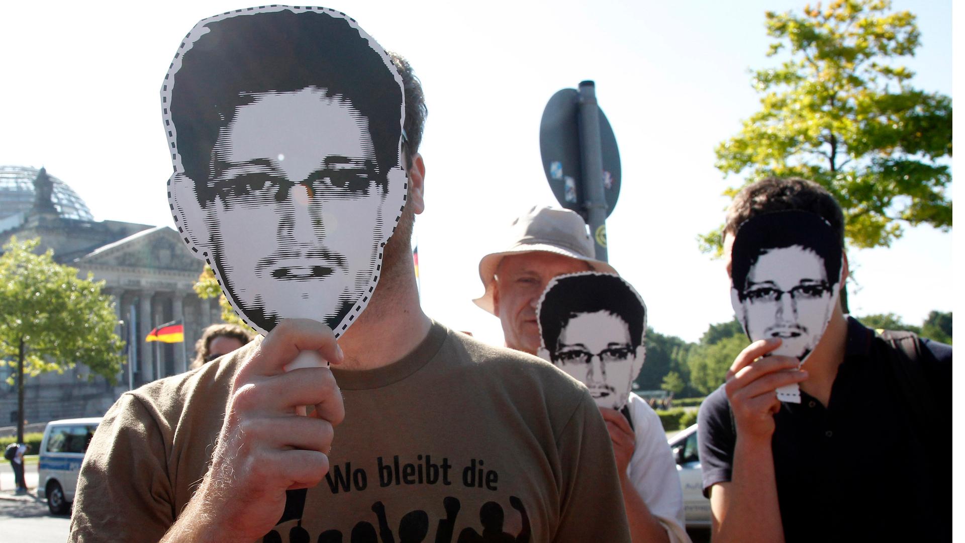 Protesters hold masks depicting former US National Security Agency contractor Edward Snowden during a demonstration in Berlin on May 22, 2014. The sentence on the shirt reads, "What has happened to revolution?"