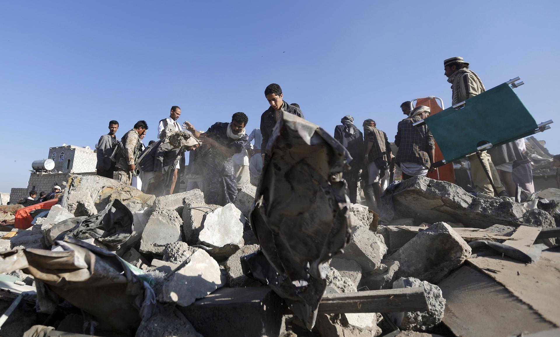 People search for survivors under the rubble of houses destroyed by an air strike near the Sanaa airport on March 26, 2015.