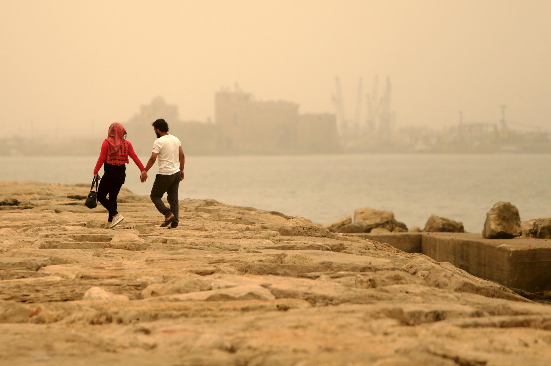 A couple walk during a sandstorm near the sea castle of the port-city of Sidon, Lebanon September 8.