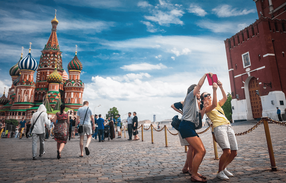 Tourists pose for a selfie outside of Saint Basil's Cathedral in Red Square.