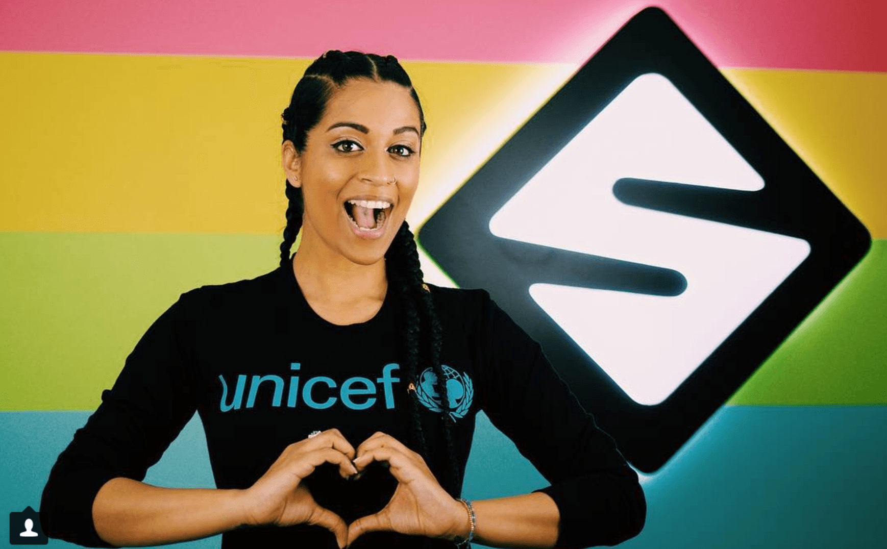 Lilly Singh poses with her hands in a heart symbol.