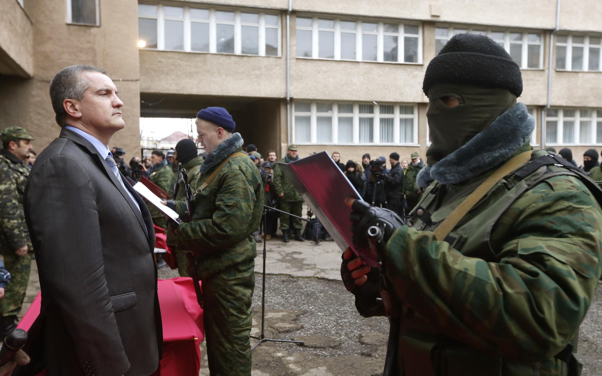 Sergei Aksyonov, Crimea's pro-Russian prime minister, stands as a member of a pro-Russian self defense unit takes an oath to Crimea government in Simferopol on March 10, 2014. Russian forces consolidated their hold on Ukraine's Crimea peninsula on Monday,