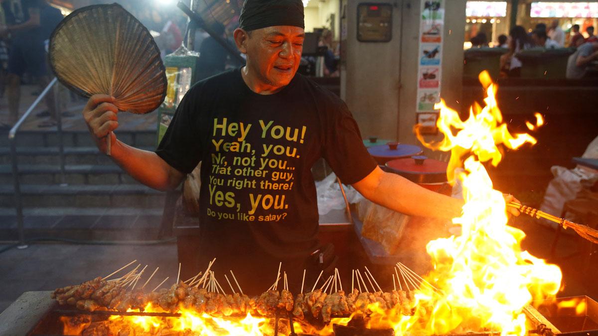 A stall helper mans a satay stand at Lau Pa Sat food center in Singapore.