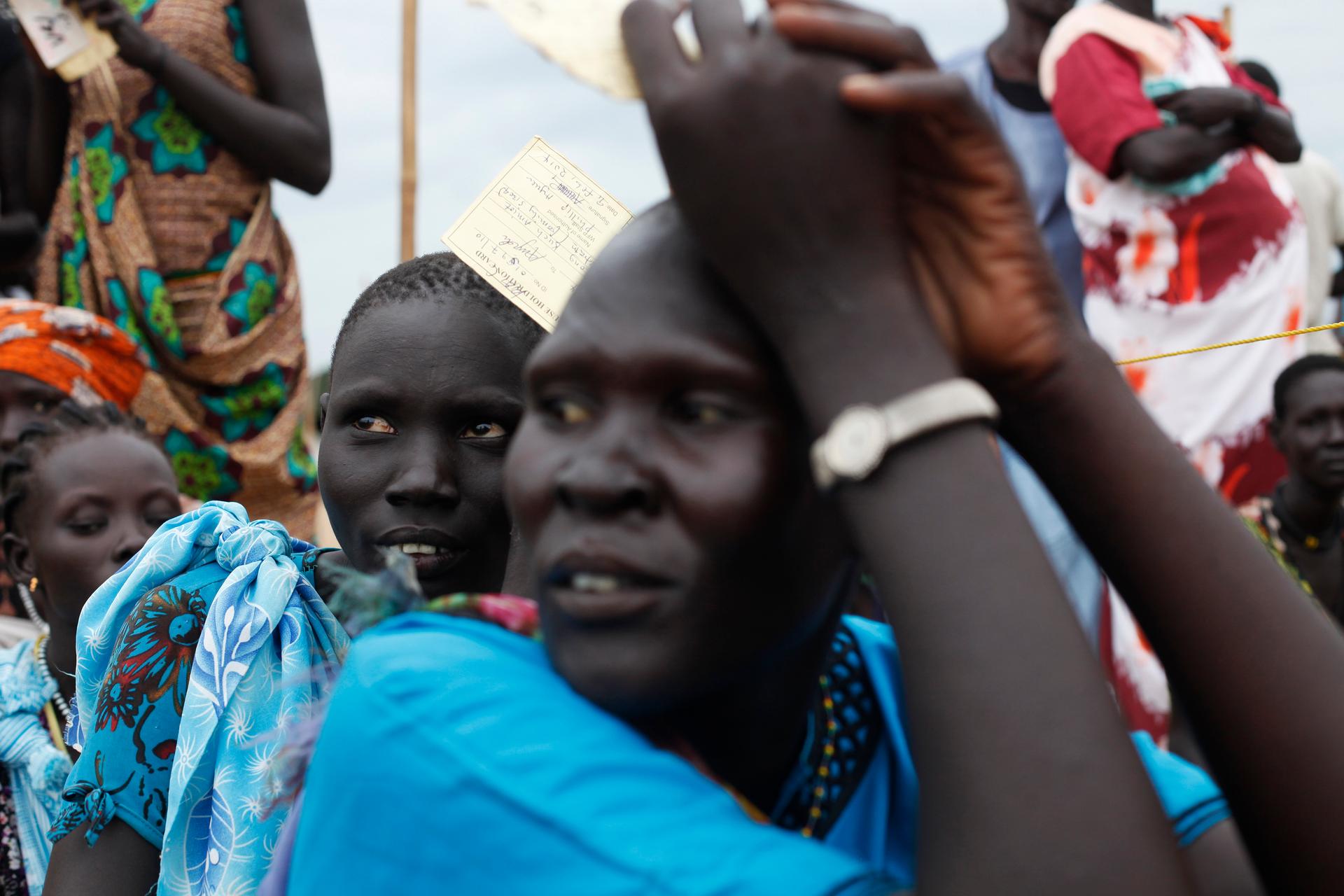 Women hold their ration cards during food distribution in Minkaman, Lakes State, June 26, 2014. About 94,000 people have sought refuge in Minkaman after fighting broke out in neighboring states, according to the International Organization for Migration.