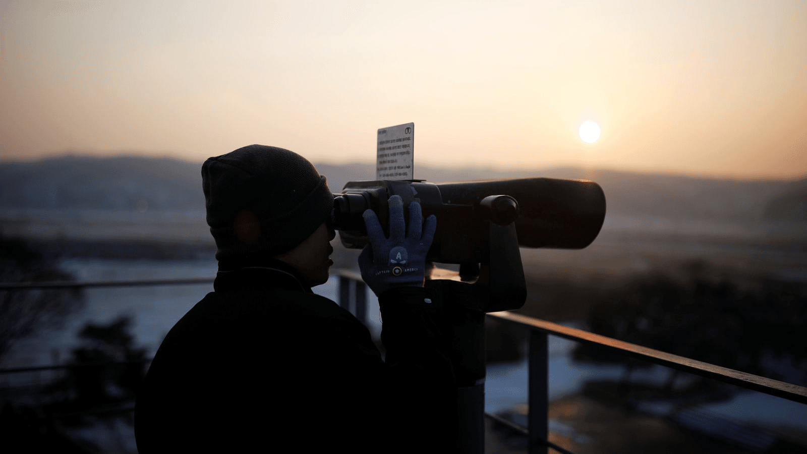 A man looks toward the north through a pair of binoculars near the demilitarized zone separating the two Koreas, in Paju, South Korea, Dec. 21, 2017.