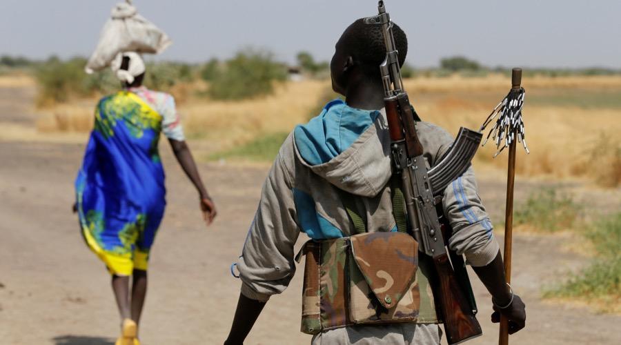 An armed man walks on a path near the village of Nialdhiu, South Sudan