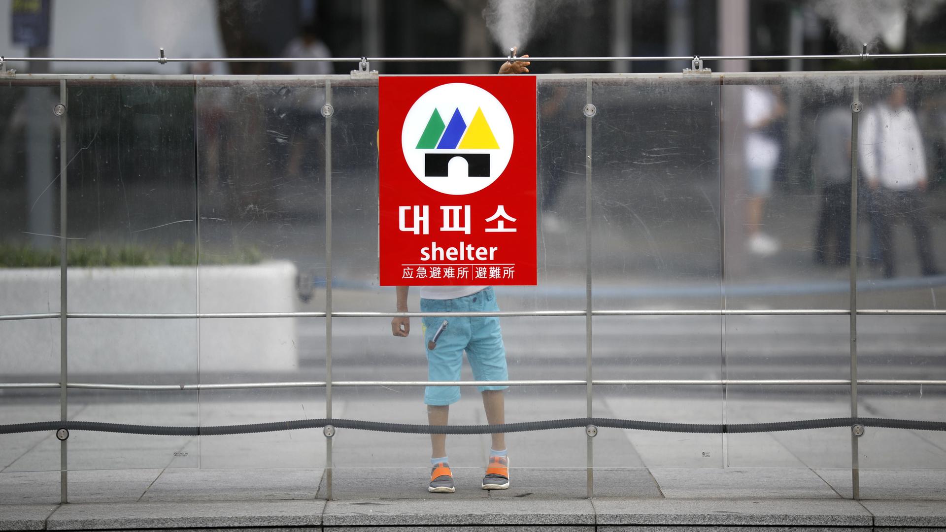 A boy plays behind a sign of shelter at an entrance of a subway station in Seoul, South Korea, August 11, 2017.