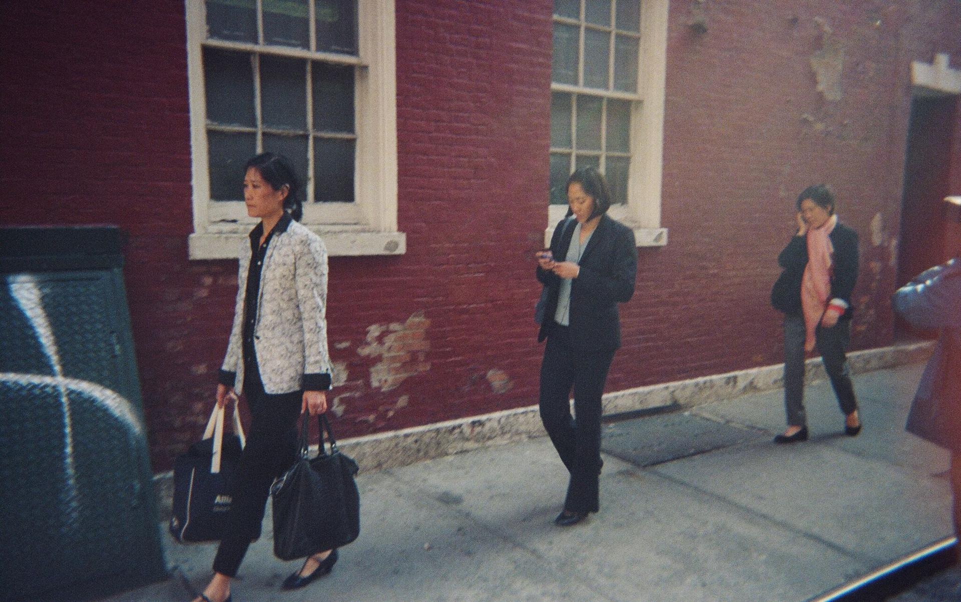 Three women walking on the sidewalk.