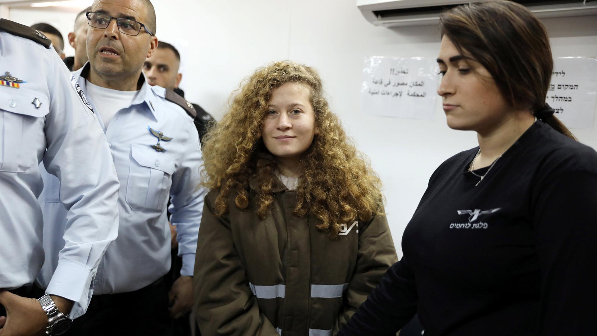 Palestinian teen Ahed Tamimi enters a military courtroom escorted by Israeli security personnel at Ofer Prison, near the West Bank city of Ramallah, Jan. 15, 2018.