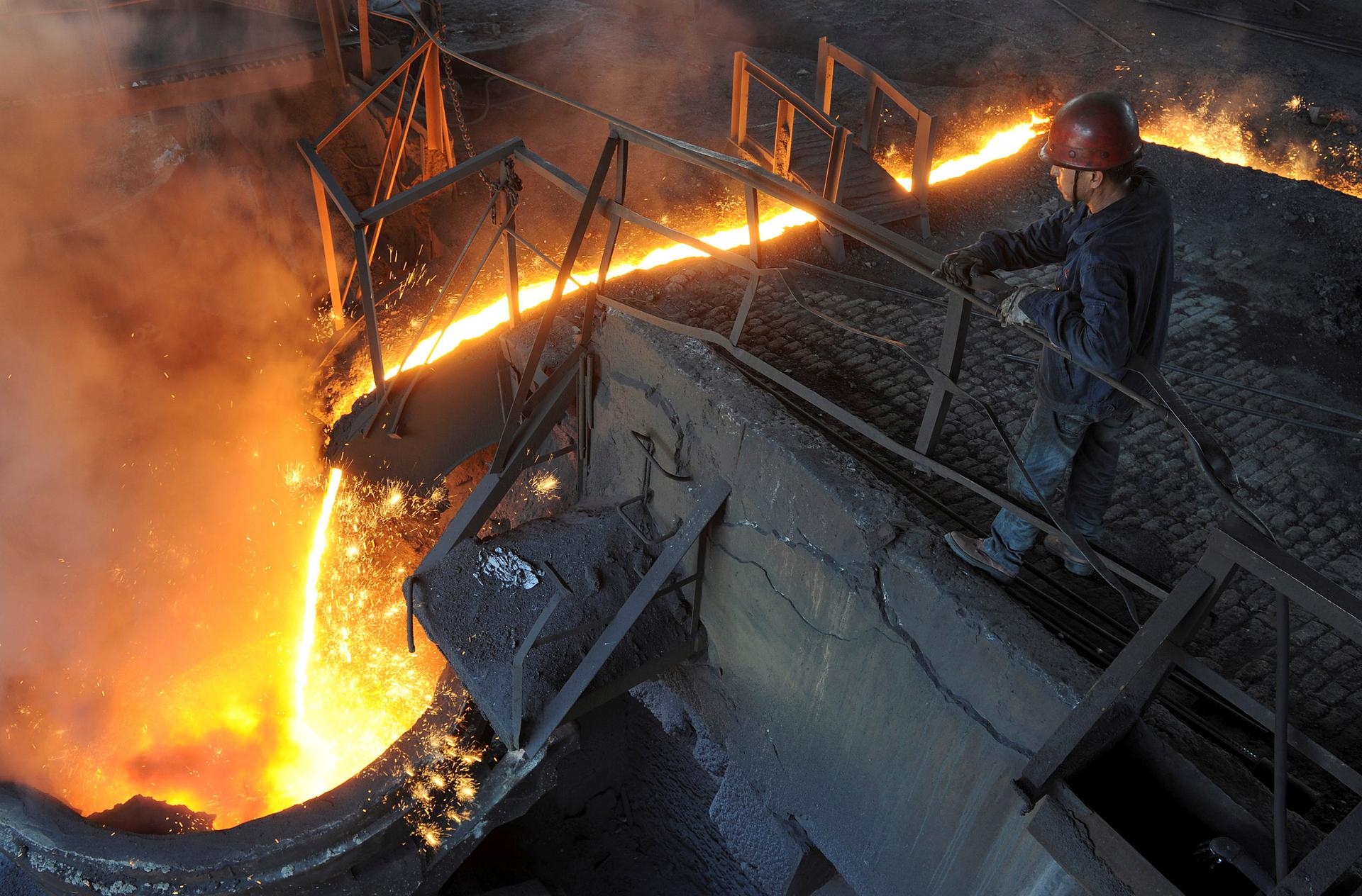 A worker monitors molten iron pouring into a furnace at steel manufacturing plant in Hefei, Anhui province, China. 