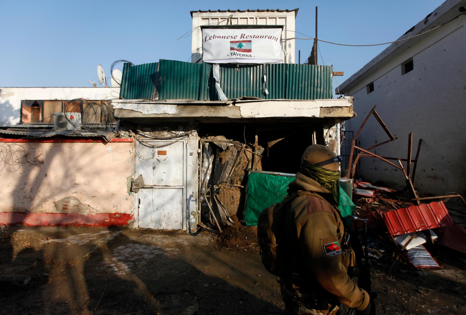 An Afghan security personnel walks past a Lebanese restaurant, the site of a suicide bombing, in Kabul January, 2014.