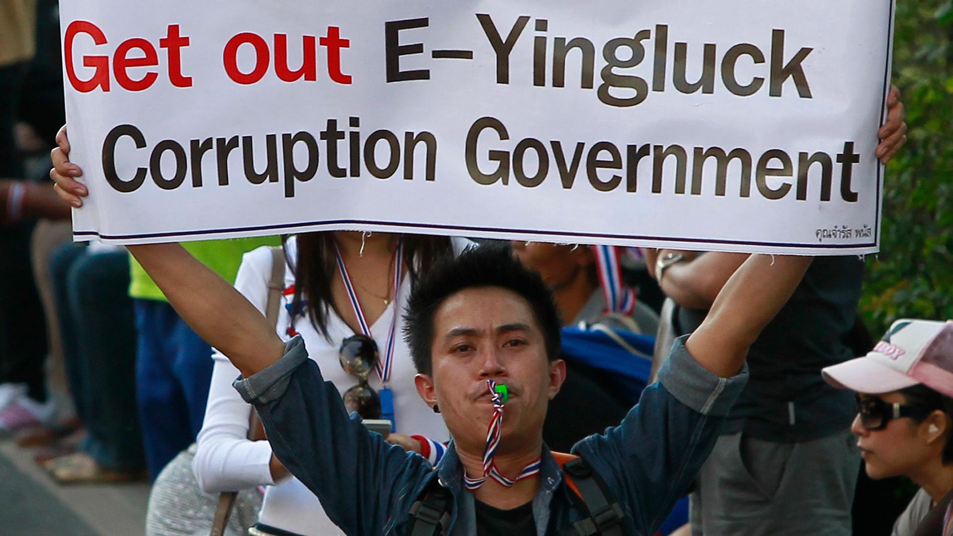 An anti-government protester blows a whistle and holds a banner during a rally in central Bangkok January 15, 2014.