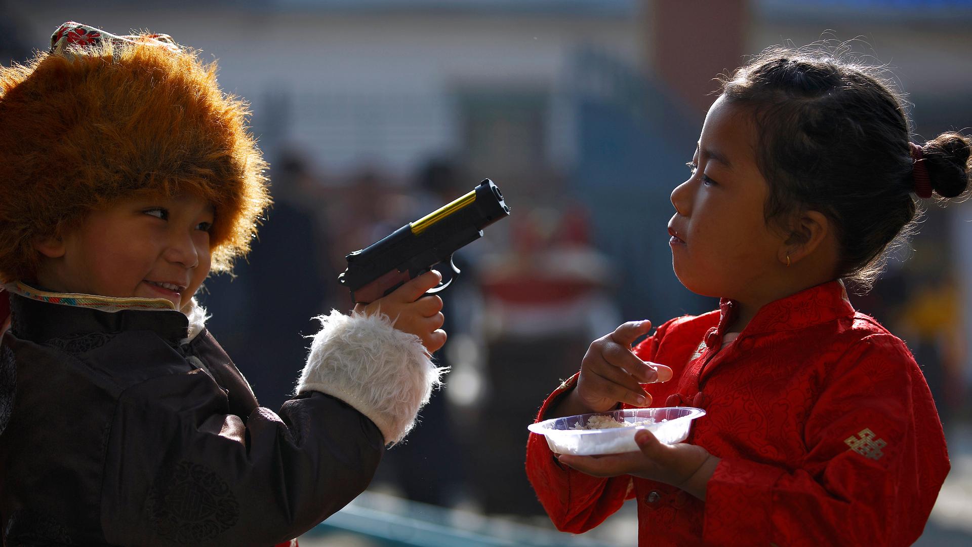 A Tibetan boy points a toy gun towards a girl during the function organized to mark "Losar" or the Tibetan New Year at a Tibetan Refugee Camp in Lalitpur.