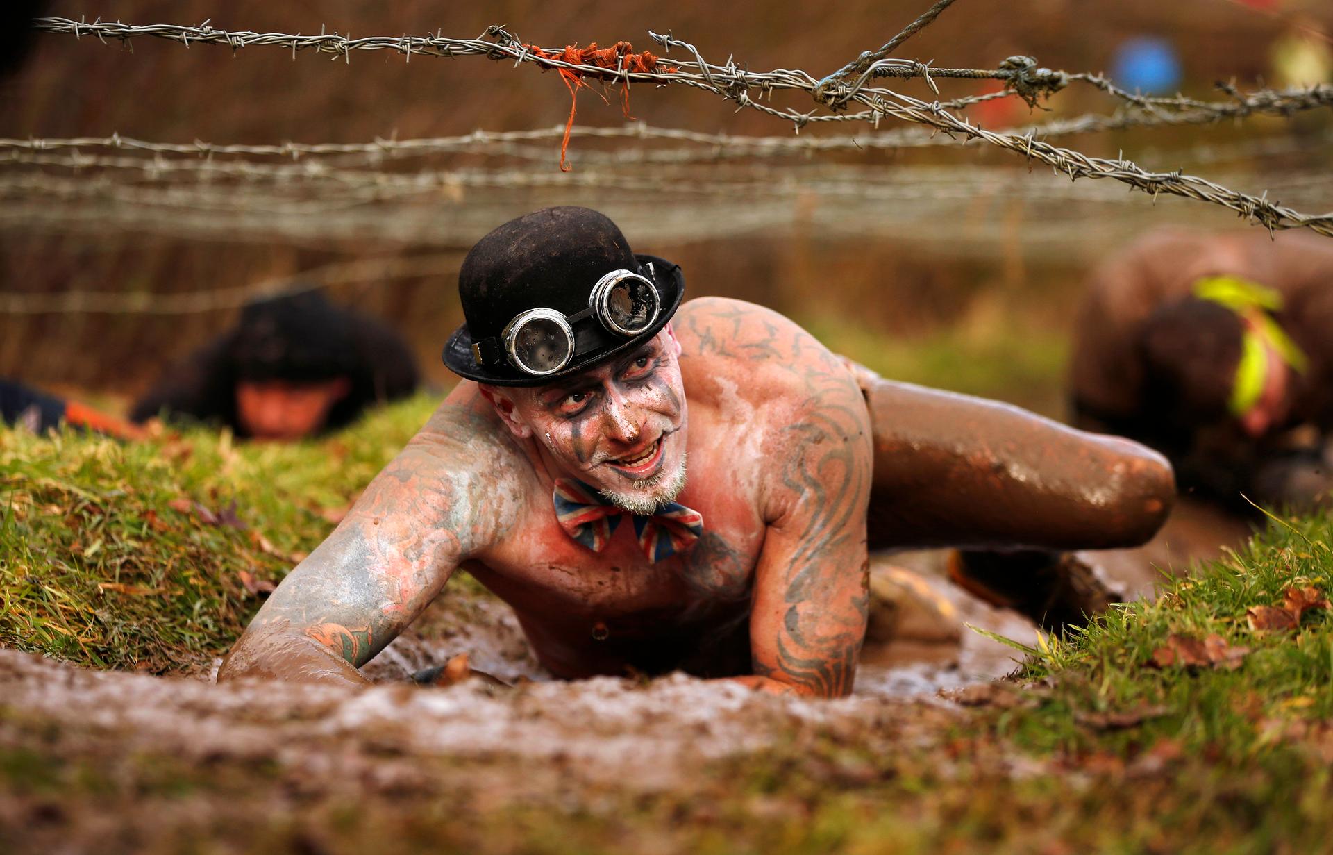 A competitor crawls beneath barbed wire during the Tough Guy event in Perton, central England February 1, 2015. The annual event to raise cash for charity challenges thousands of international competitors in a cross country run followed by an assault cour