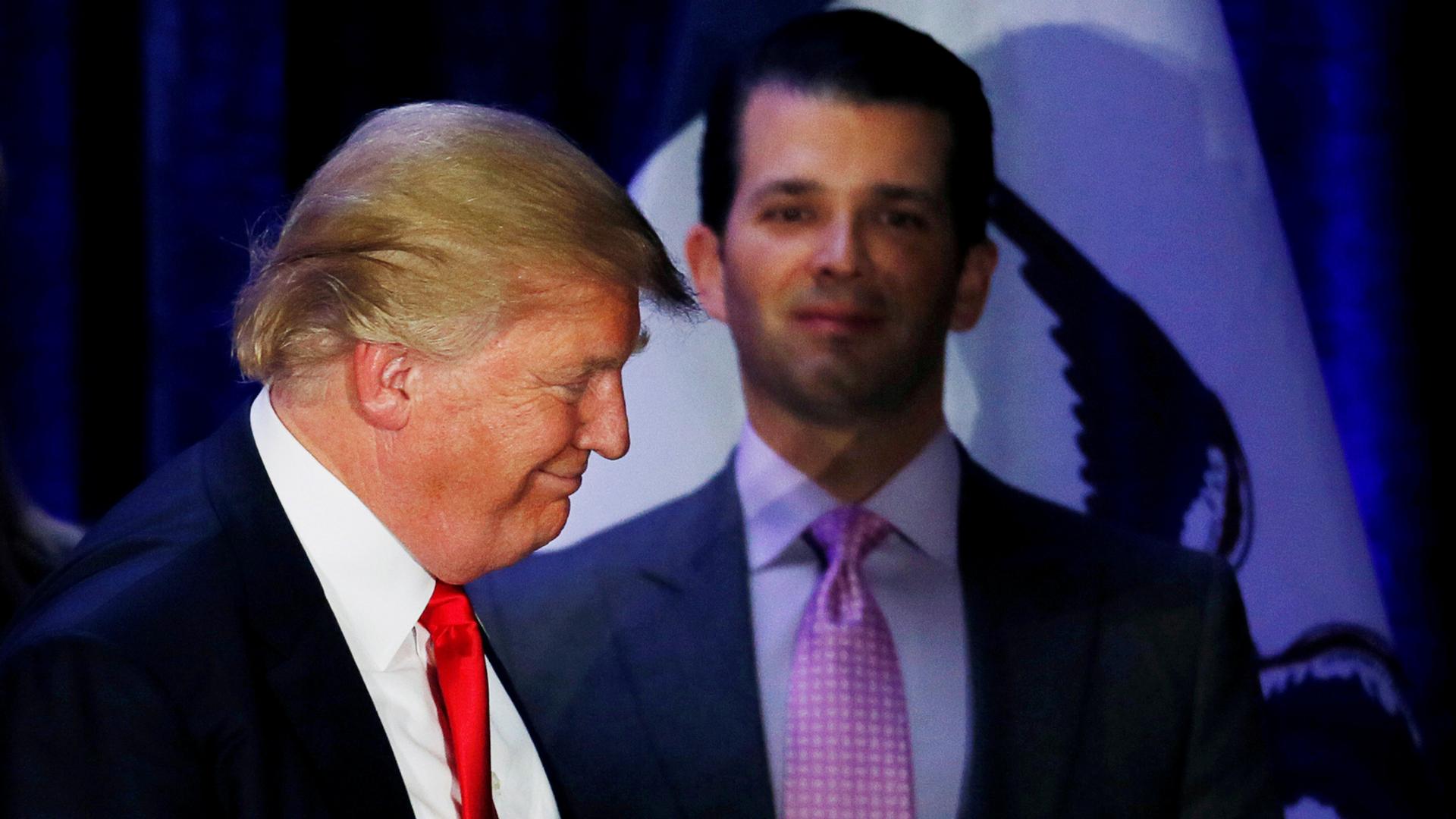 Donald Trump Jr. stands profile in the background watch his father exit the stage left.