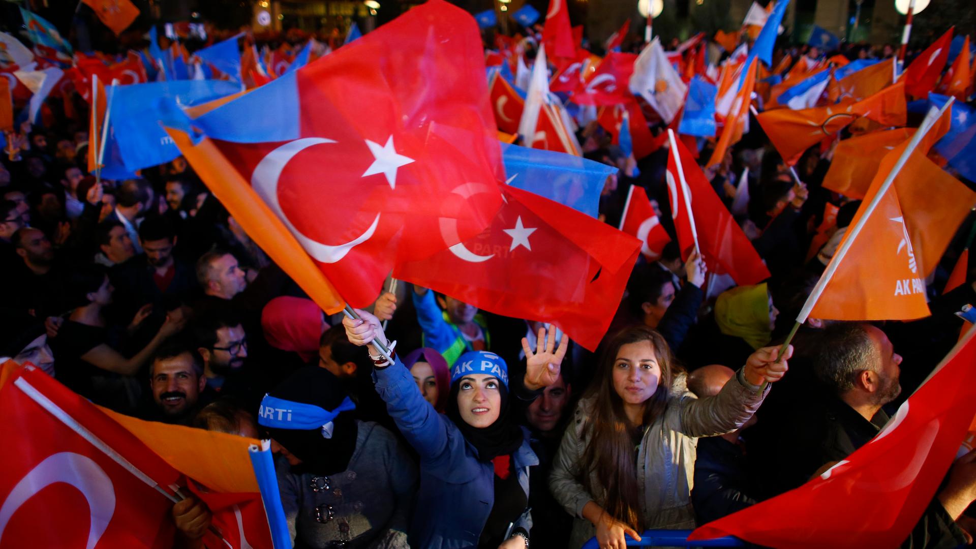 Women wave flags outside the AKP headquarters in Ankara, Turkey. Turkish Prime Minister Ahmet Davutoglu described the outcome of a general election which swept his AKP back to a parliamentary majority on Sunday as a victory for democracy.