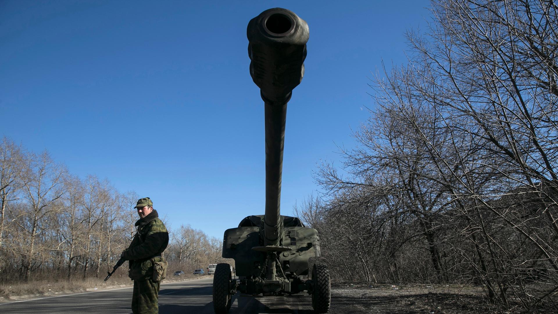 An armed man stands near a truck of the separatist self-proclaimed Donetsk People's Republic army towing a mobile artillery cannon, February 24, 2015.