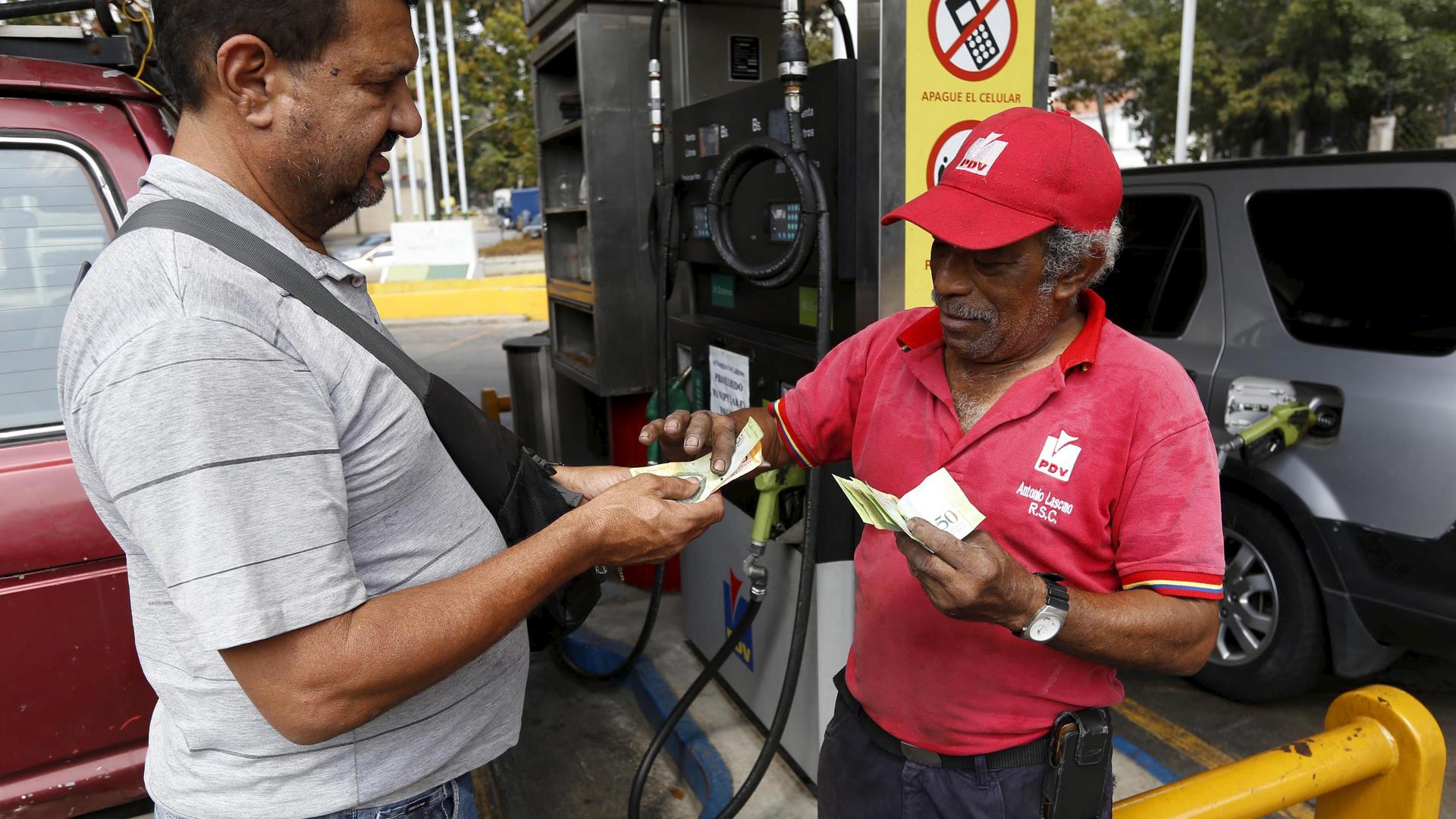 A man pays after filling up his car with fuel at a gas station which belongs to PDVSA in Caracas, Venezuela February 19, 2016.