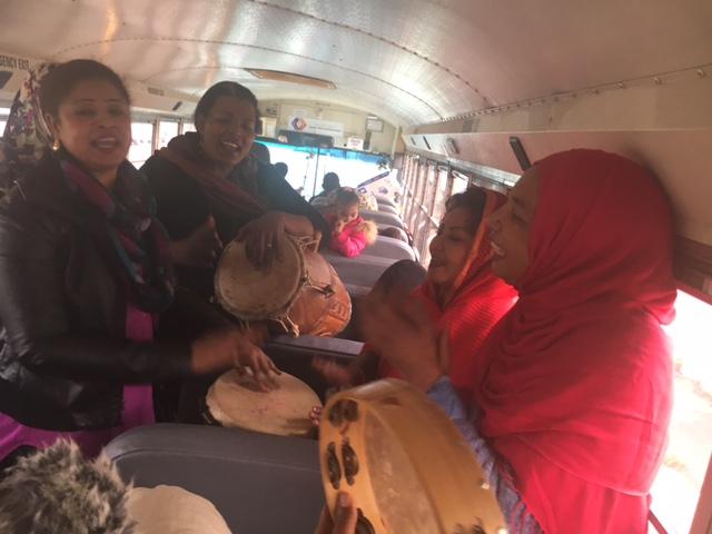 A group of women on a bus, with drums, singing