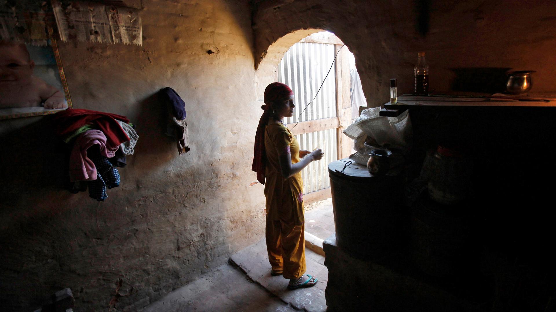 A woman laborer watches television inside her house at the compound of a brick factory at Libbar Hari in the northern Indian state of Uttarakhand.