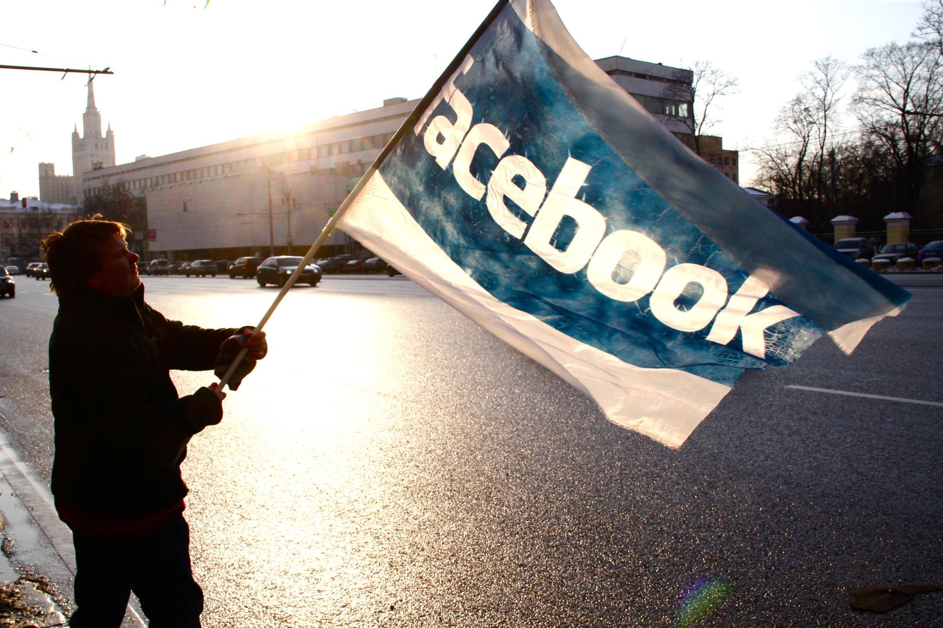 A protester in Russia waves a Facebook flag.