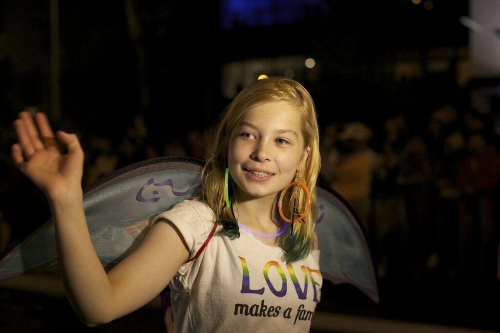 A girl with rainbow colored earring and a T-shirt that reads "LOVE makes a family"