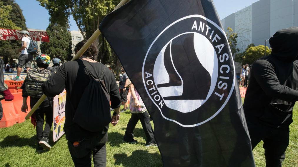 An antifa activist carries a flag of the movement, which features a logo of two flags.