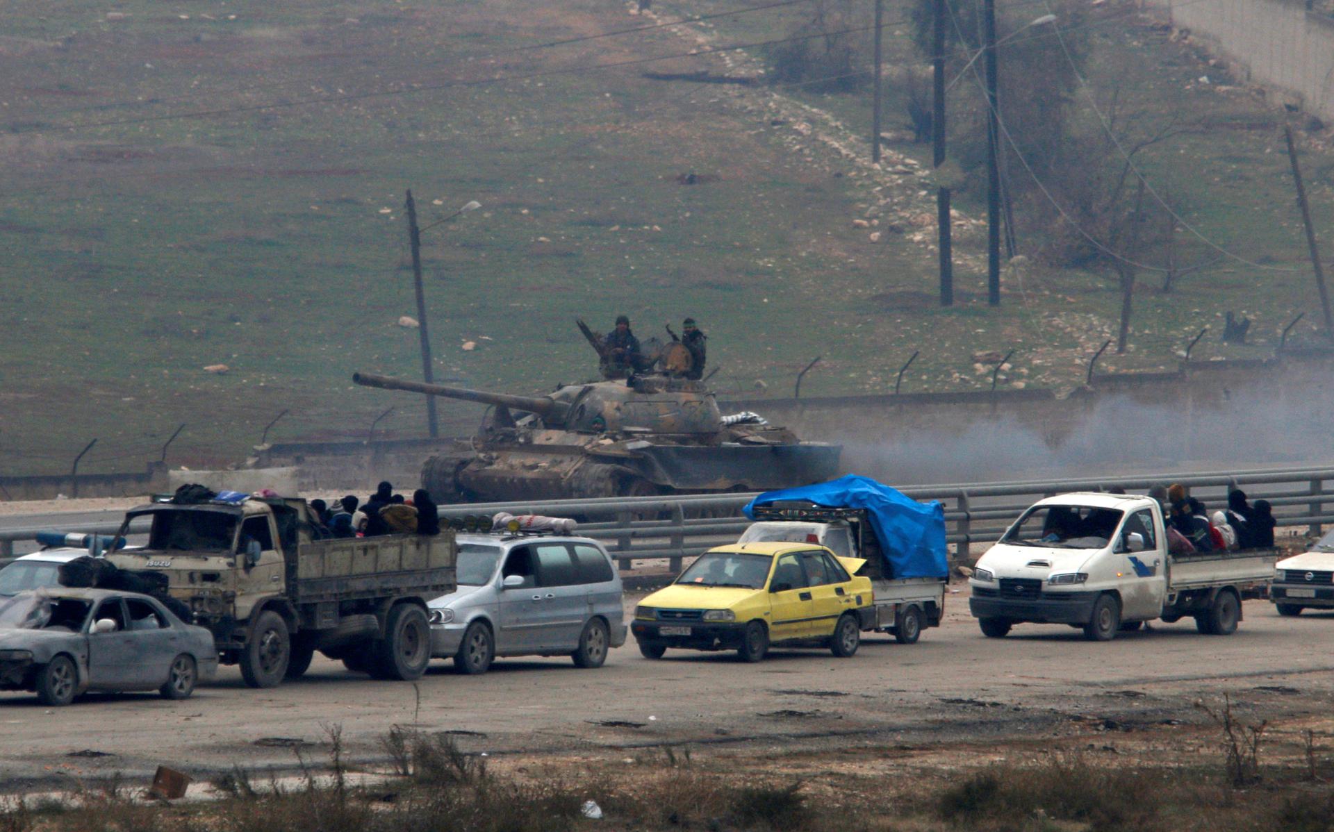 Forces loyal to Syria's President Bashar al-Assad sit on a tank as a convoy of buses and other vehicles try to evacuate