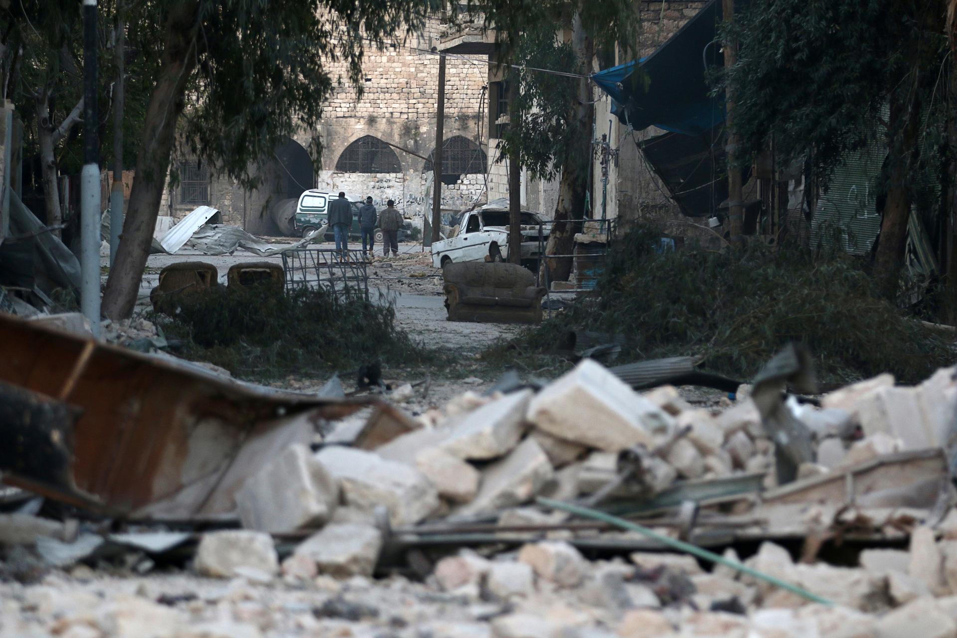 People walk near rubble of damaged buildings