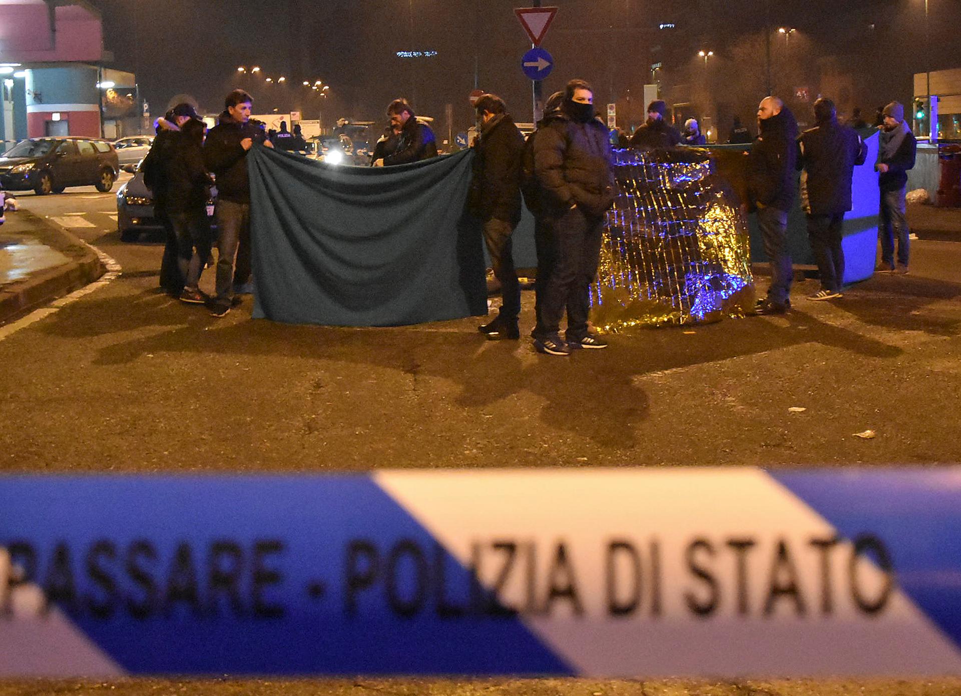 Italian police officers work next to the body of Anis Amri