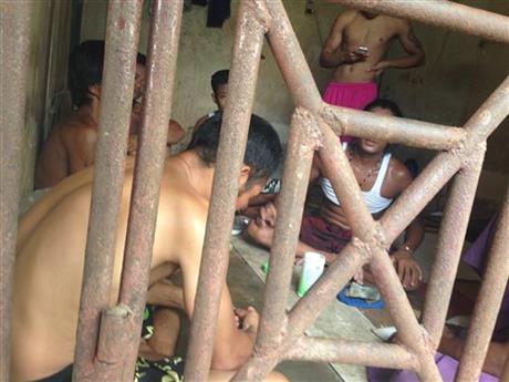 In this Saturday, Nov. 22, 2014 photo, Thai and Burmese fishing boat workers sit inside a cell at the compound of a fishing company in Benjina, Indonesia. The imprisoned men were considered slaves who might run away. They said they lived on a few bites of